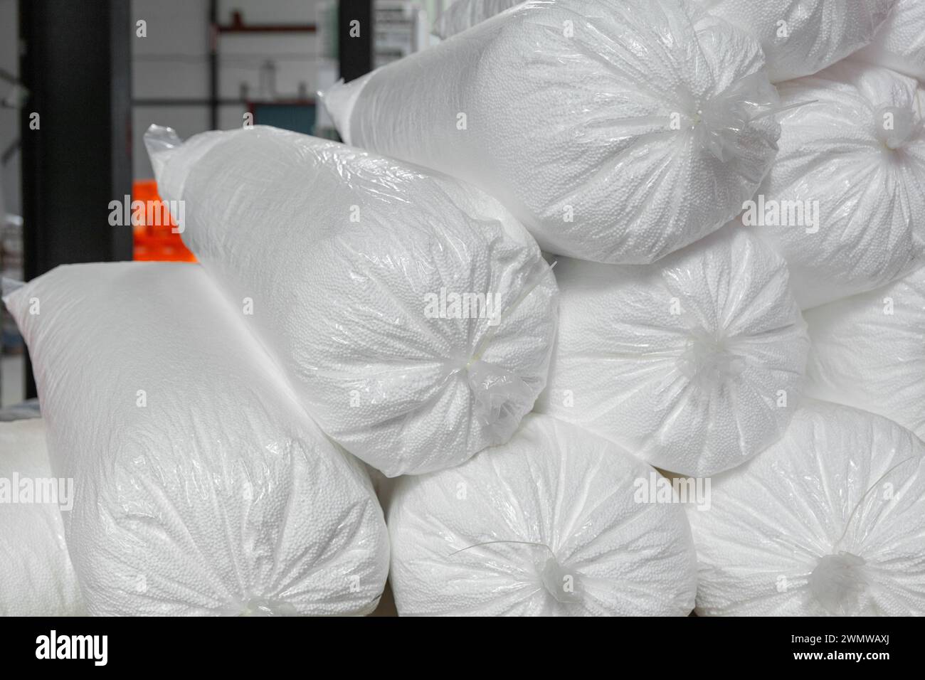 A bunch of bags of loose granular foam in a commercial warehouse. Loose foam is used as insulation to fill voids in building structures. Stock Photo