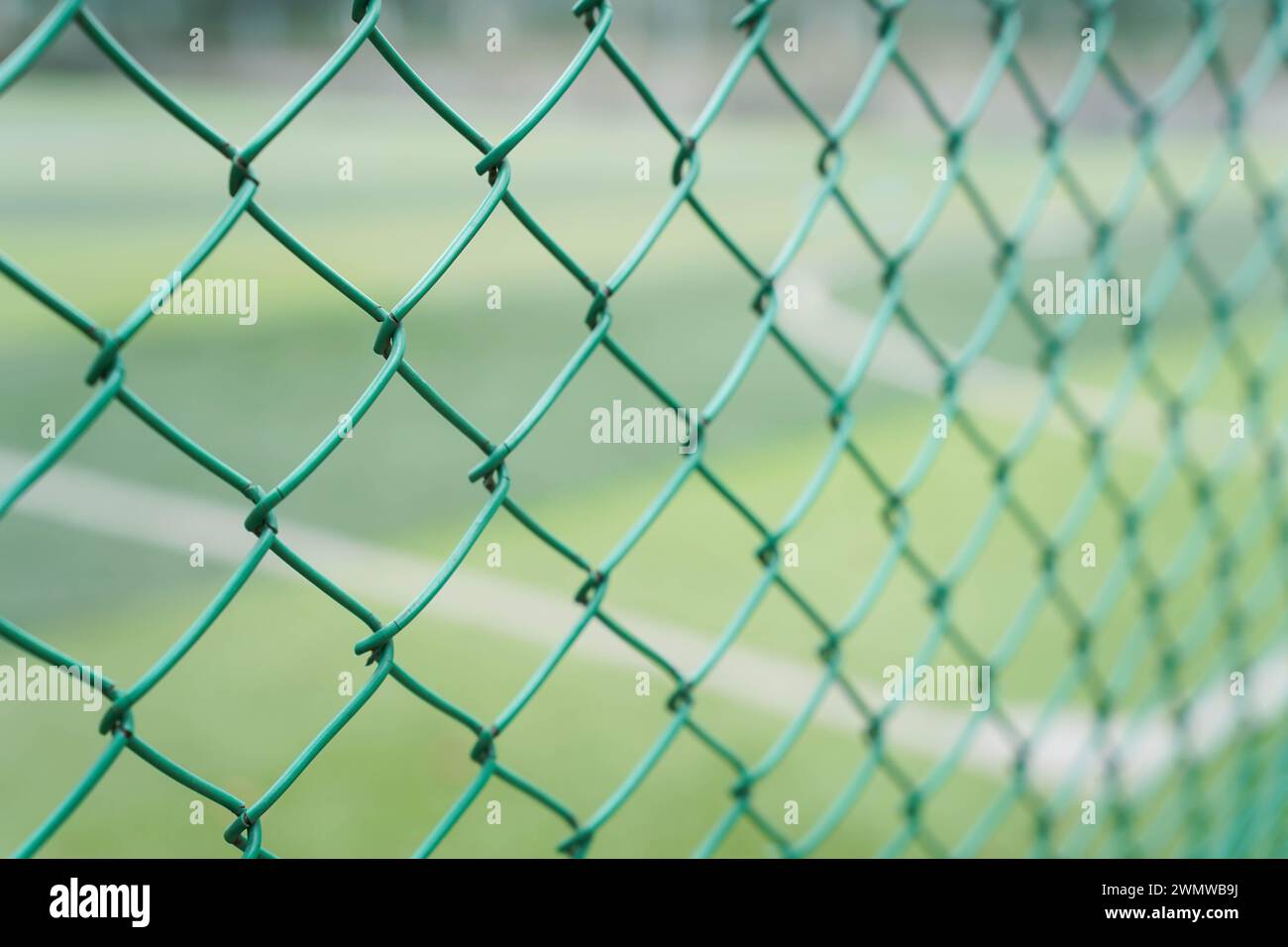 green barbed wire / steel mesh wire fence on blur football playground ...