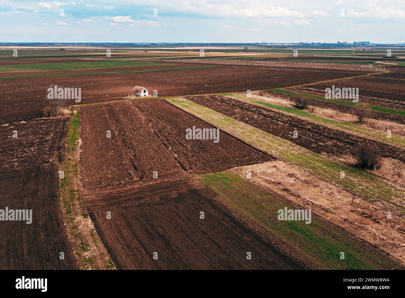 Aerial view of abandoned farmhouse in the middle of cultivated fields on overcast winter day, drone pov high angle view Stock Photo