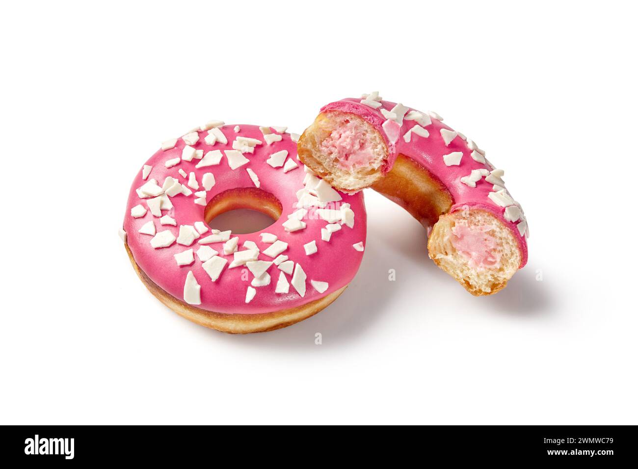 Appetizing soft fluffy donuts with creamy berry filling and vibrant pink icing sprinkled with white chocolate chips. Popular confectionery Stock Photo