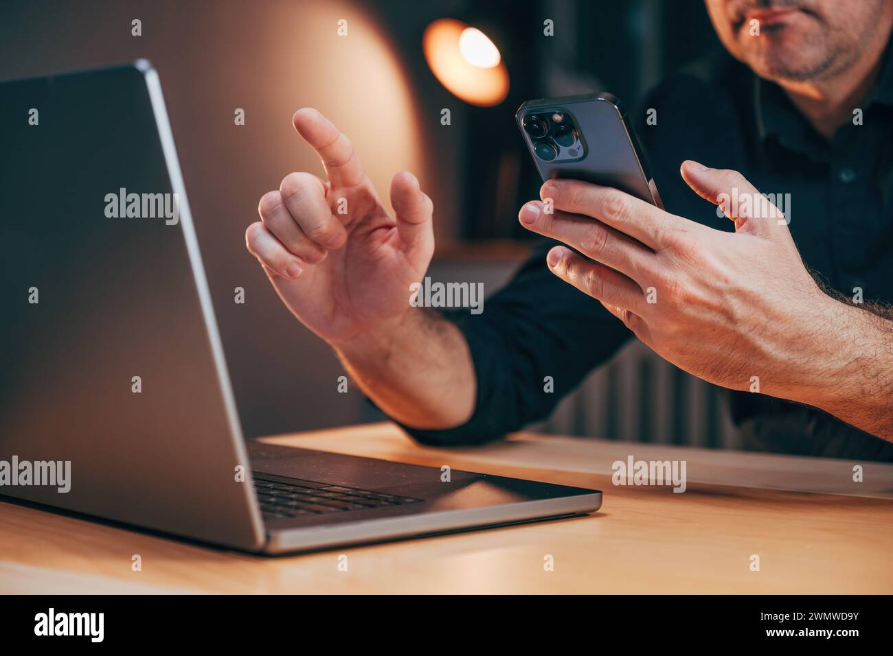 Businessman using laptop computer and smartphone in office while working overtime, selective focus Stock Photo