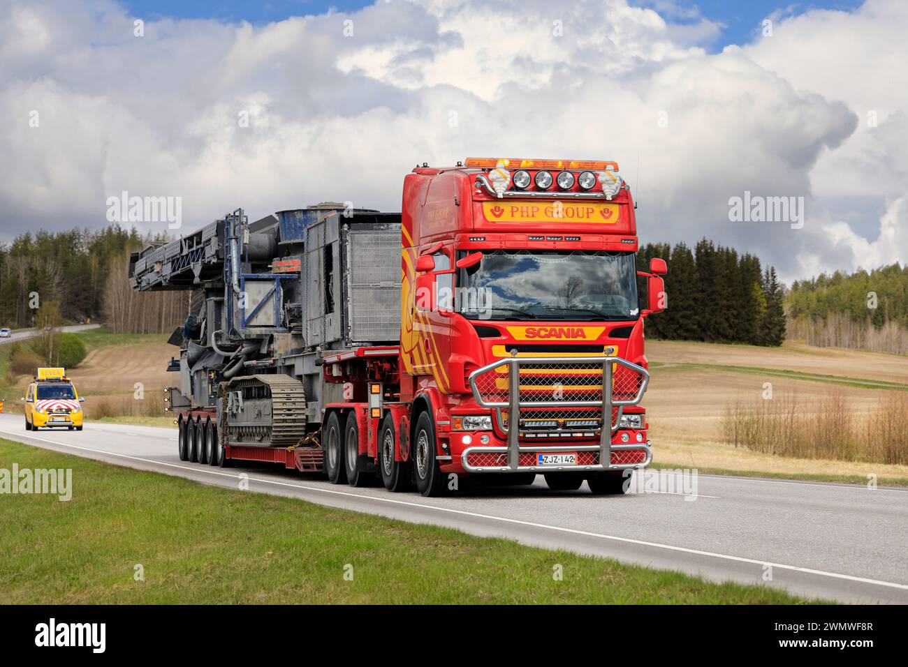 Scania truck PHP Group Oy hauls Volvo Penta powered crushing equipment as oversize load, assisted by escort vehicle. Salo, Finland. May 13, 2022. Stock Photo