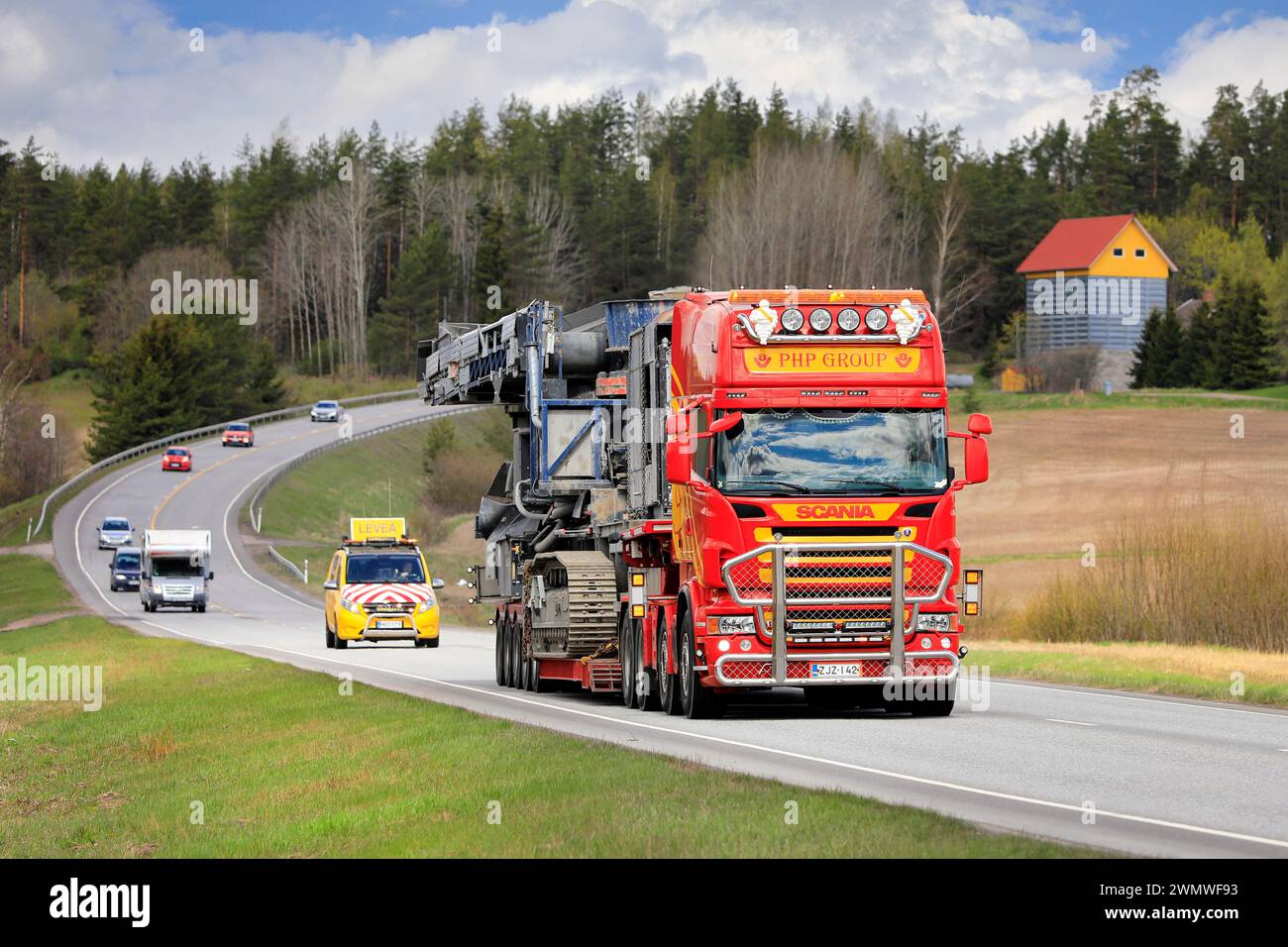 Scania truck PHP Group Oy hauls Volvo Penta powered crushing equipment as oversize load, assisted by escort vehicle. Salo, Finland. May 13, 2022. Stock Photo