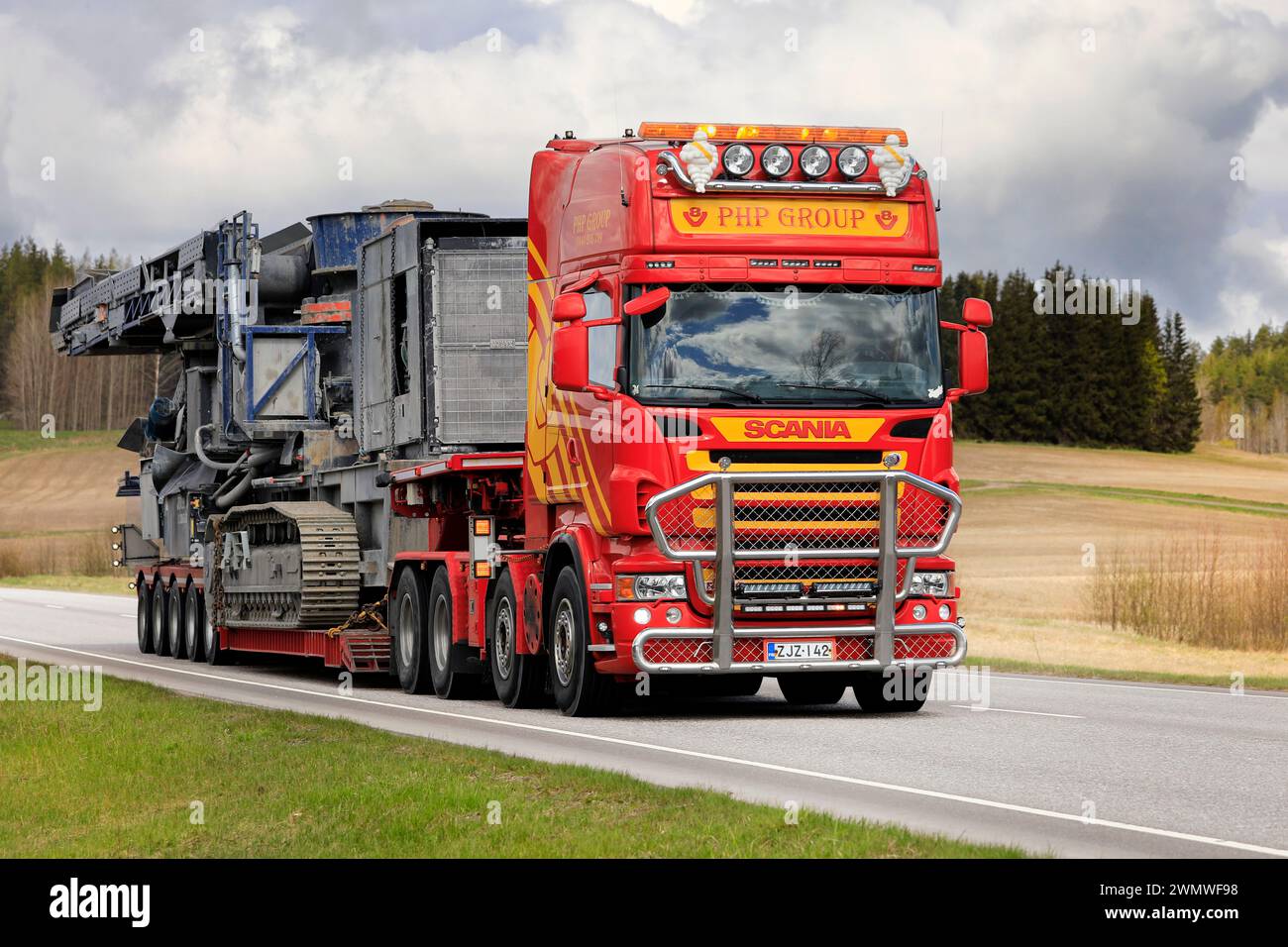 Scania truck PHP Group Oy hauls Volvo Penta powered crushing equipment as oversize load on highway 52. Salo, Finland. May 13, 2022. Stock Photo