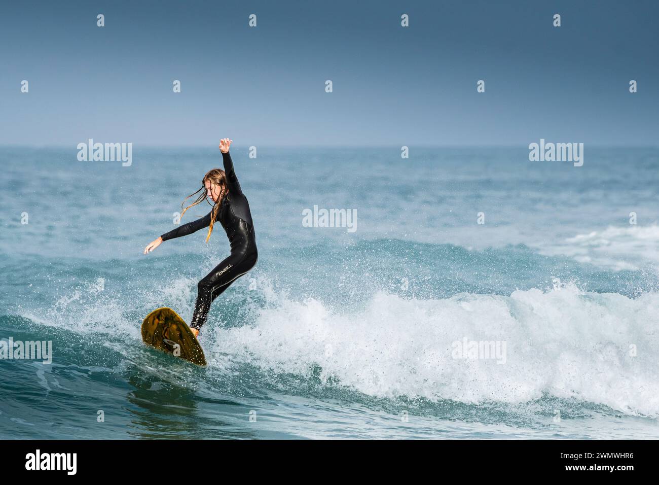 A younhg surfer riding a wave at Fistral in Newquay in Cornwall in the ...