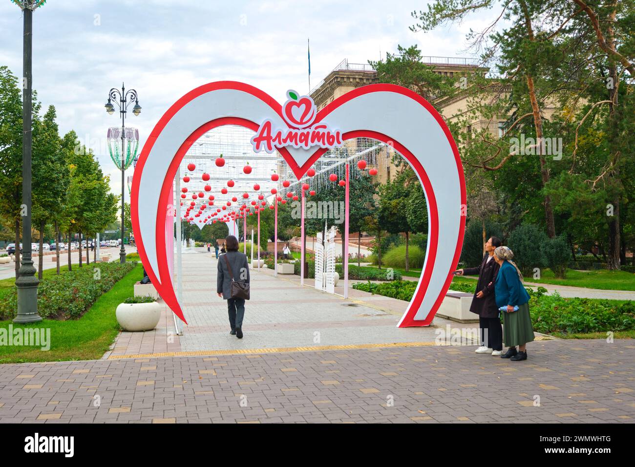 A cute pedestrian sidewalk covered tunnel, breezeway with hanging red apples. Part of the annual apple festival in Almaty, Kazakhstan. Stock Photo