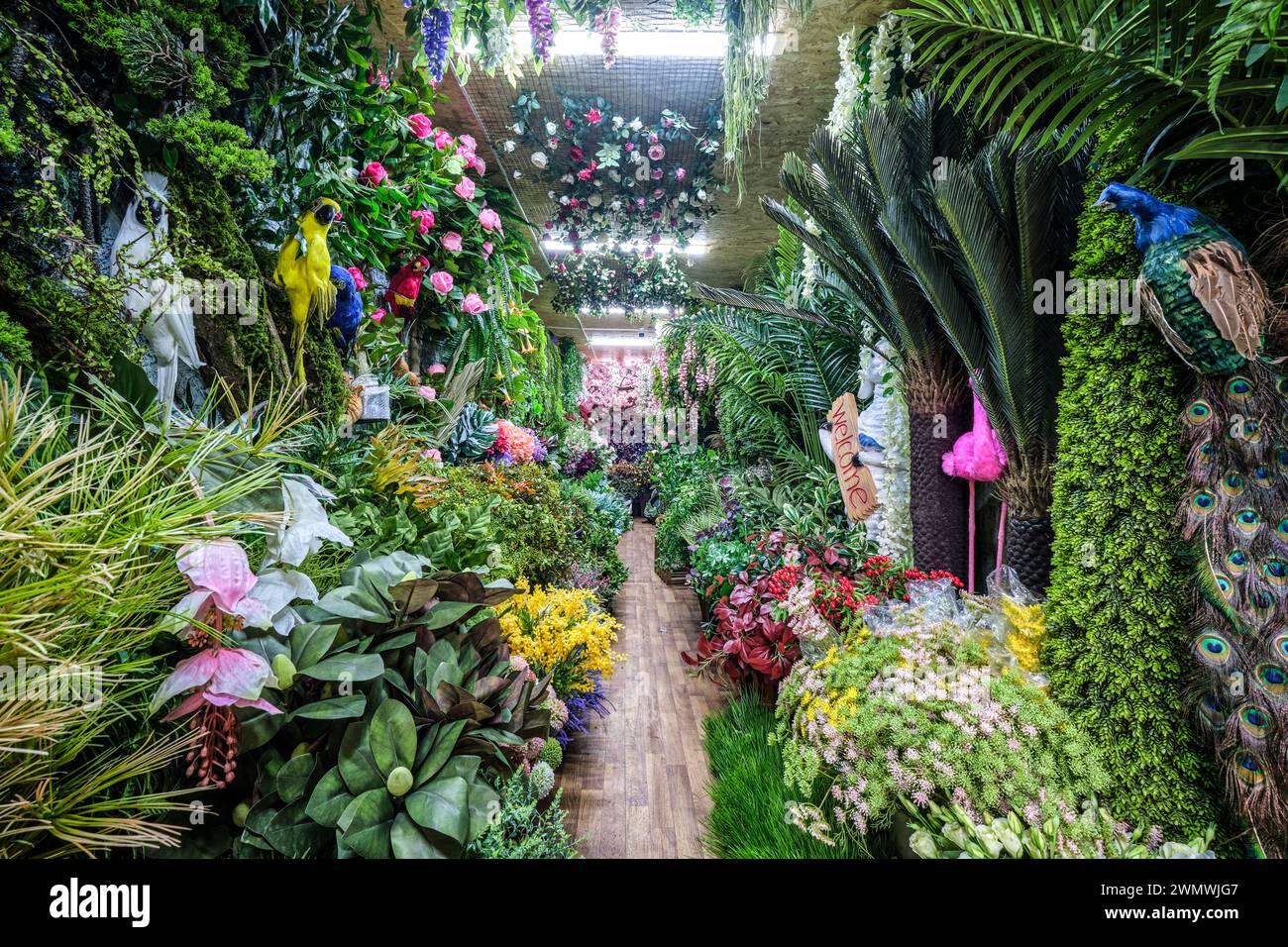 A view inside a shop that sells artificial, plastic, fake plants, flowers, birds, ferns. At the Barakholka shipping container local market in Almaty, Stock Photo