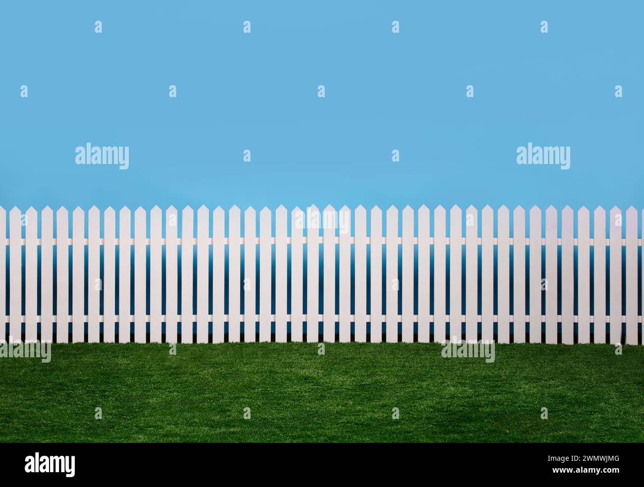 A white picket fence with green grass and a blue sky background Stock ...