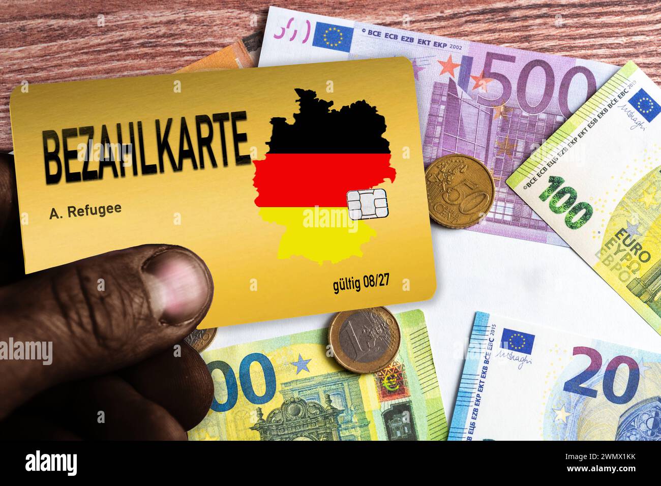 Augsburg, Bavaria, Germany - February 28, 2024: Migrant holding a payment card for refugees and asylum seekers in front of euro banknotes. PHOTOMONTAGE *** Migrant hält eine Bezahlkarte für Flüchtlinge und Asylanten in der Hand vor Euro Geldscheinen. FOTOMONTAGE Stock Photo