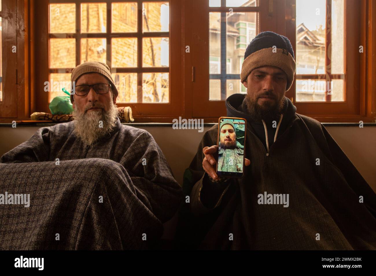 A brother holds a smart phone displaying the photos of Azad Yousuf ...