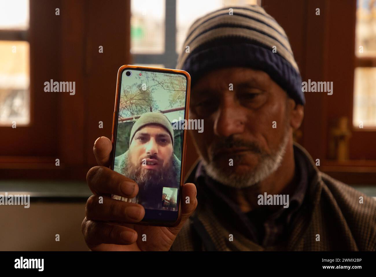 A father of Azad Yousuf Kumar, holds a smart phone displaying the