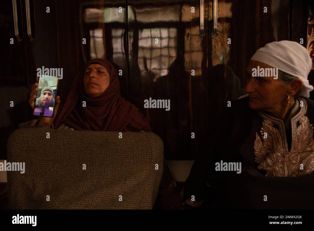 A mother of Azad Yousuf Kumar, holds a smart phone displaying the 