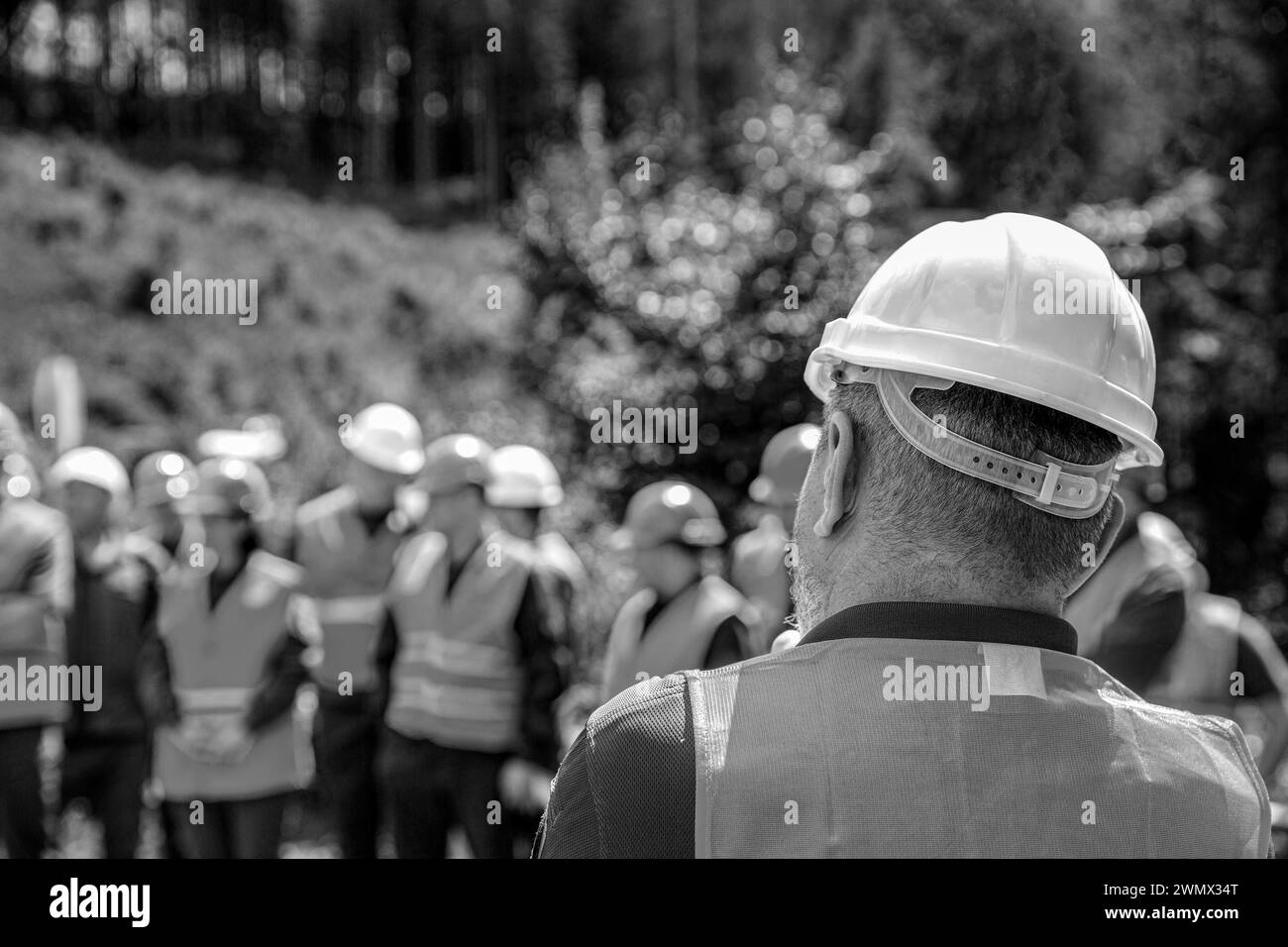 Skillful worker stand together showing teamwork. Industrial people and manufacturing labor concept. Worker group wearing vest, safety. Architector Stock Photo