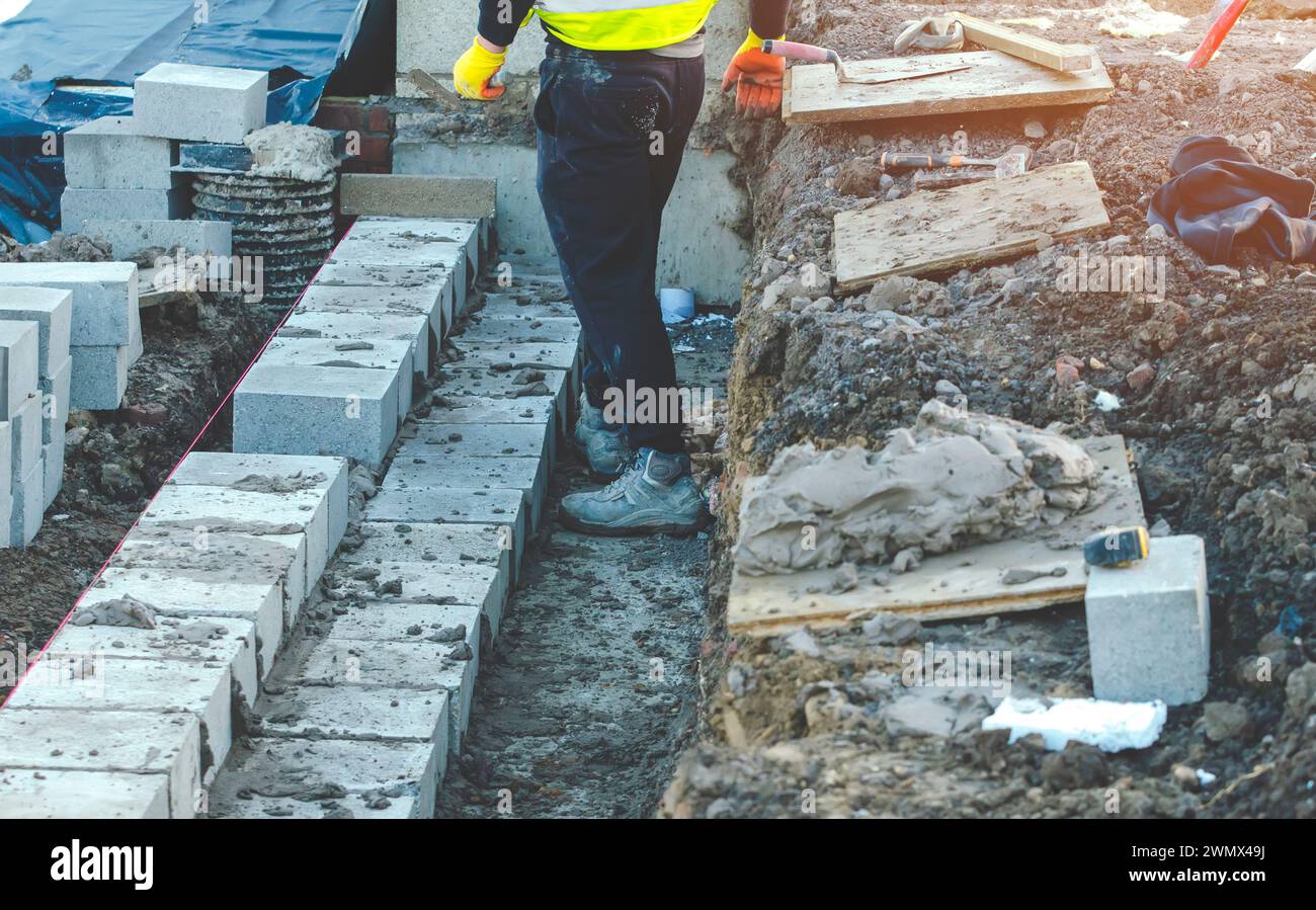 Hard working bricklayer laying concrete blocks on top of concrete ...