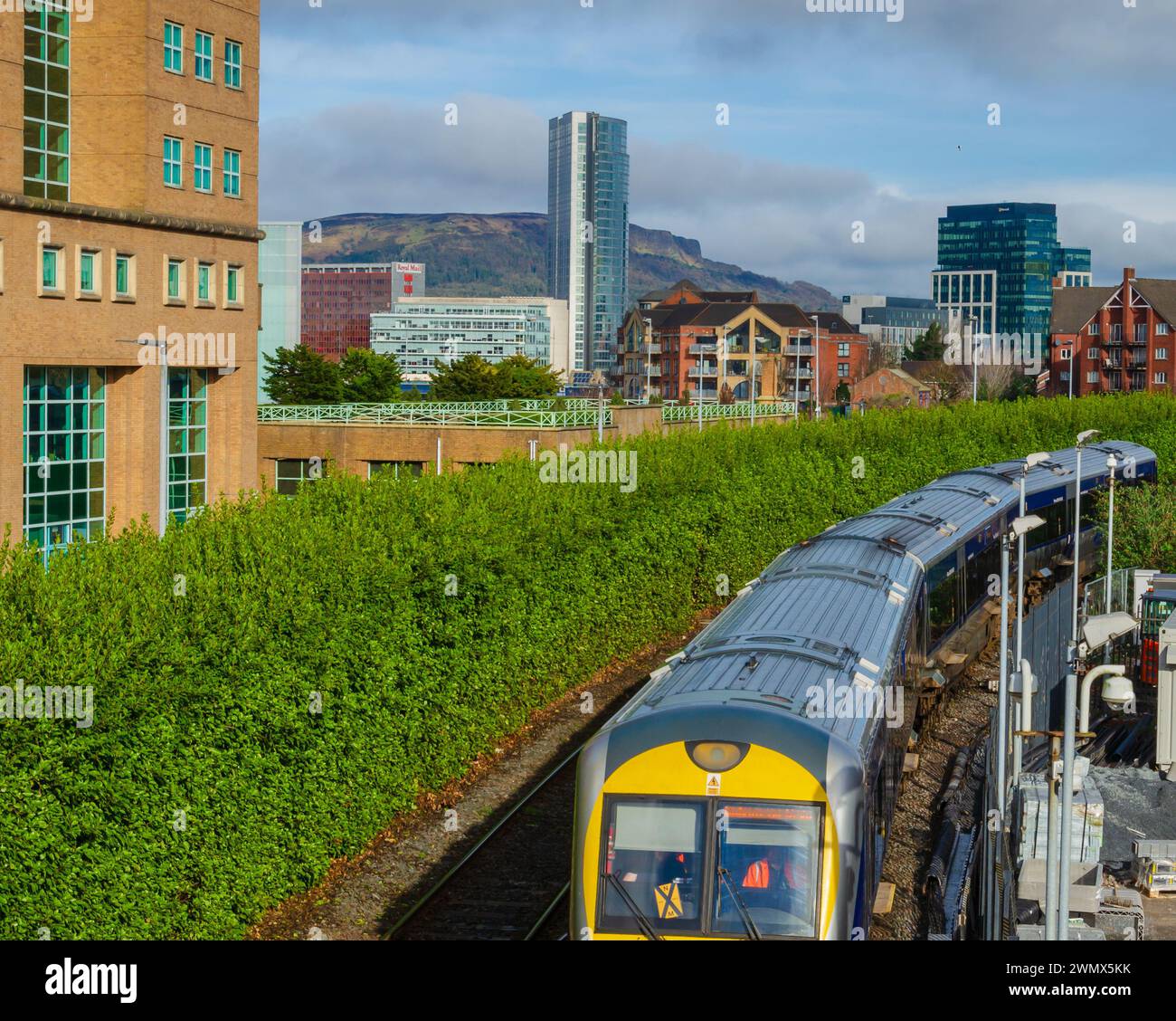 Belfast County Antrim Northern Ireland February 23 2024 - Train entering the station at Lanyon Place with  city skyline behind Stock Photo