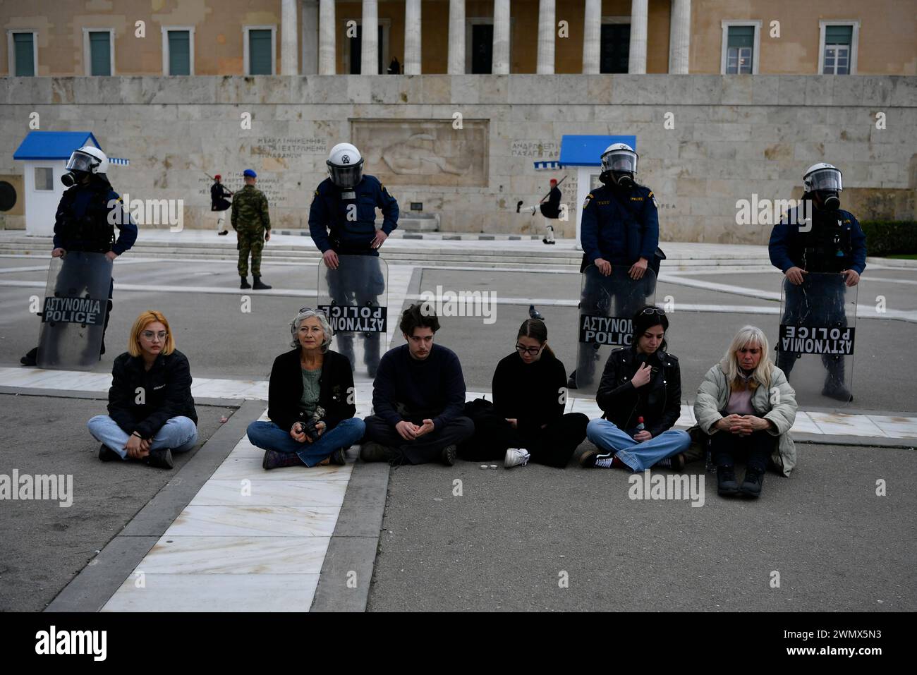Protesters sit in front of riot police during a rally in Athens, Greece ...