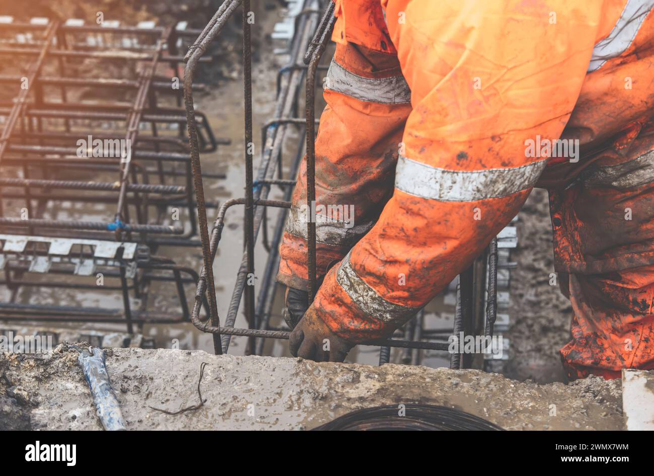 A worker uses steel tying wire to fasten steel rods to reinforcement ...