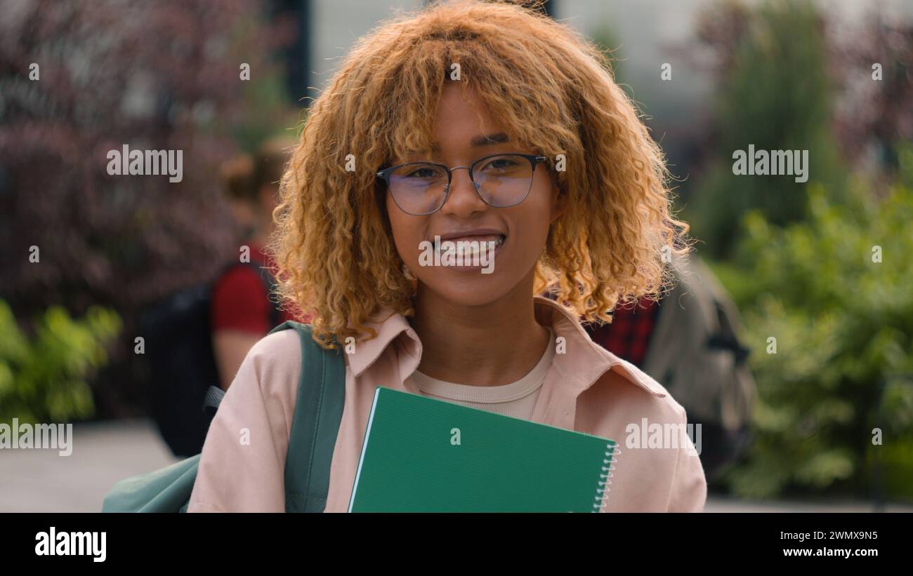 Gen z happy African American smiling student girl holding book textbook ...