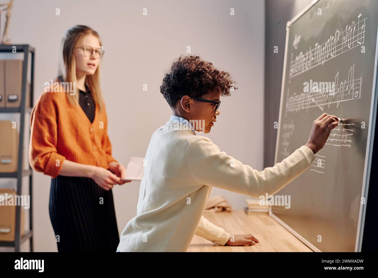 Selective focus shide view shot of African American boy writing music notes on blackboard during solfeggio lesson Stock Photo