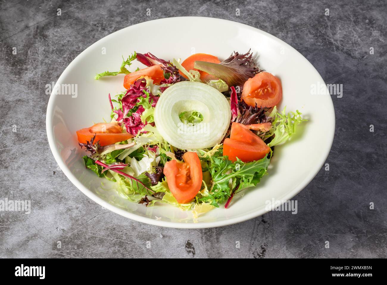 Green vegan salad from green leaves mix and vegetables. Top view on gray stone table Stock Photo