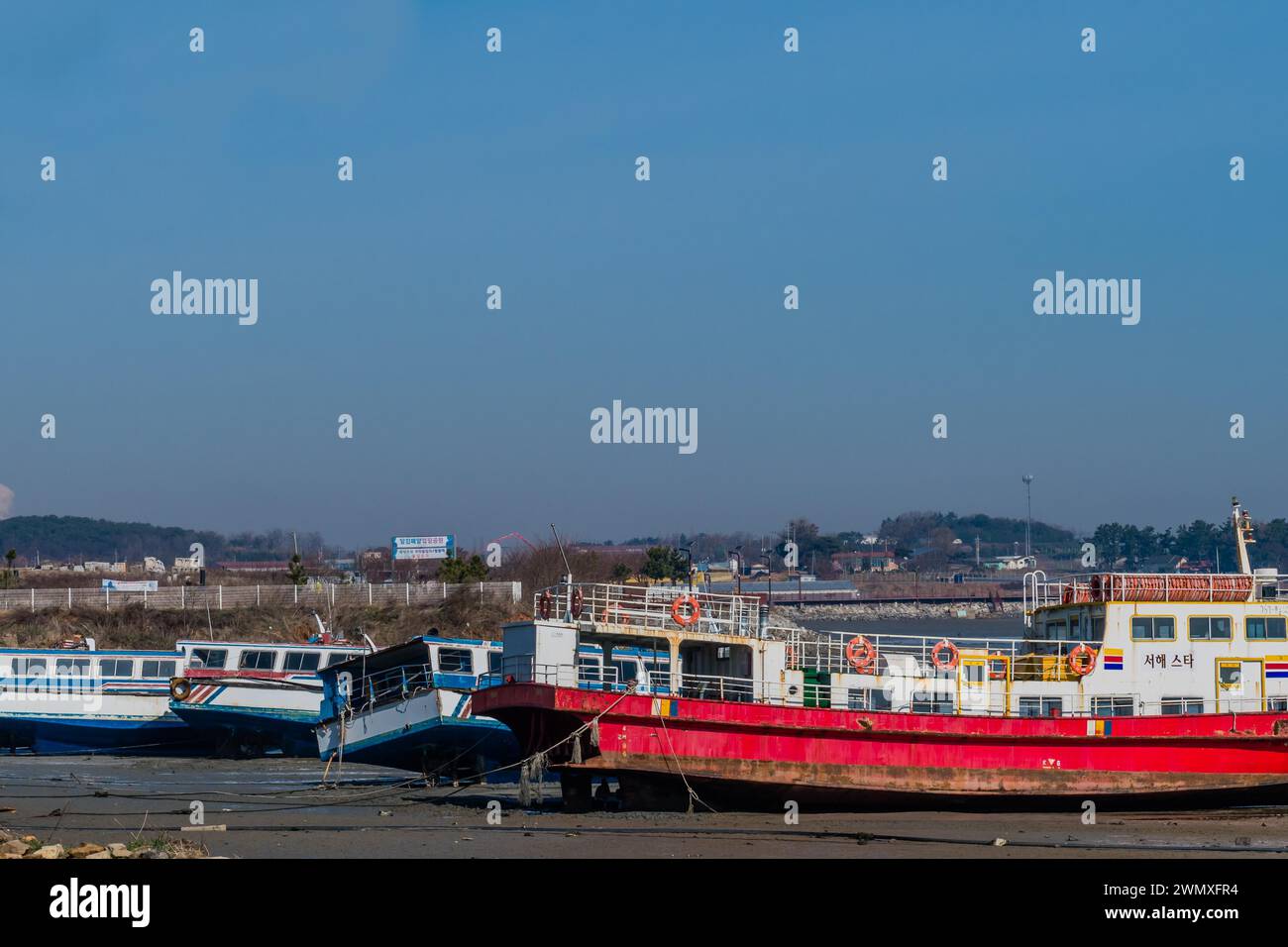 Multiple boats docked on a riverbed with clear blue skies in Pyteakeong, South Korea Stock Photo