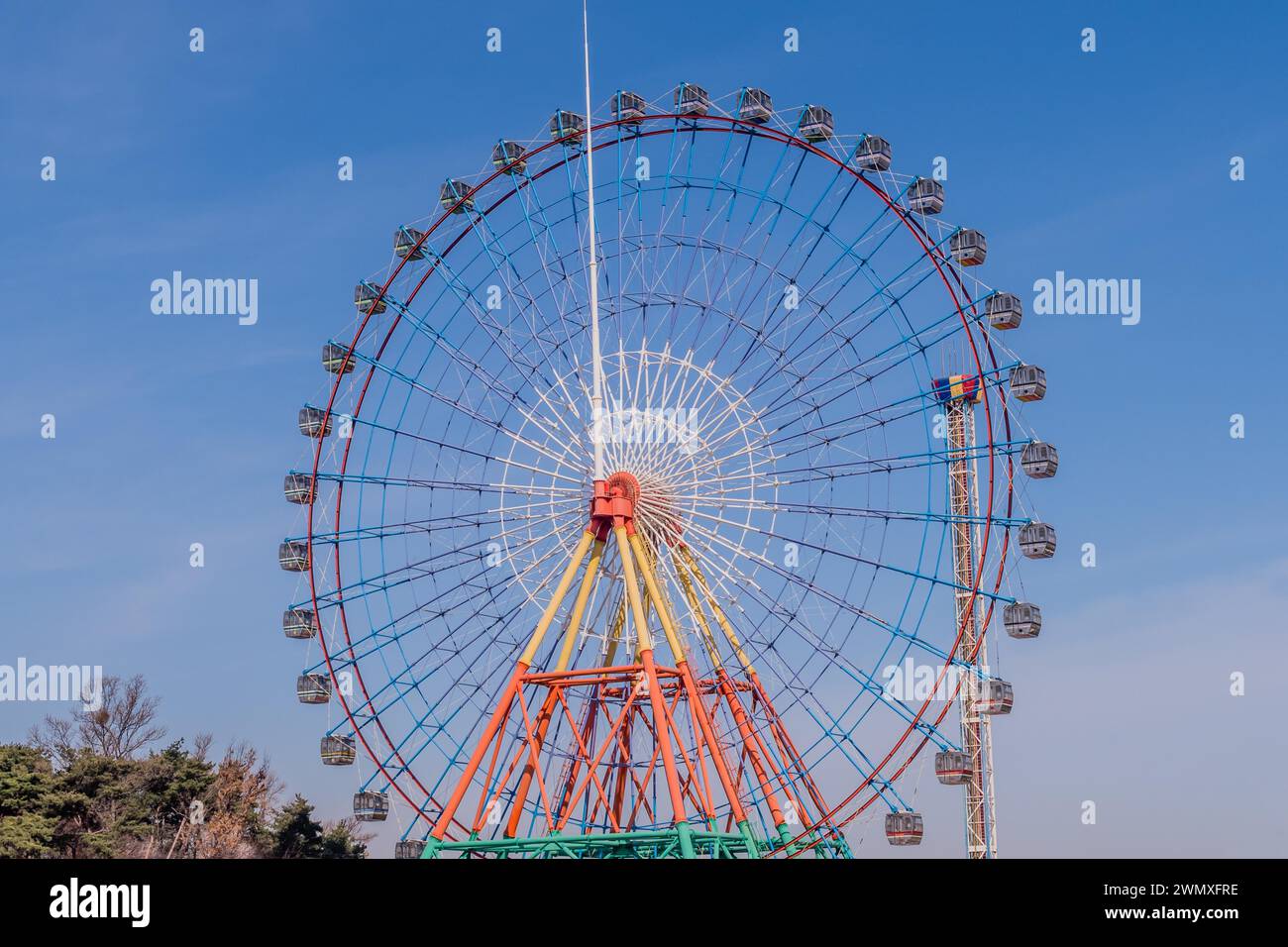 Colorful ferris wheel against blue sky with low wispy clouds in Donjin ...