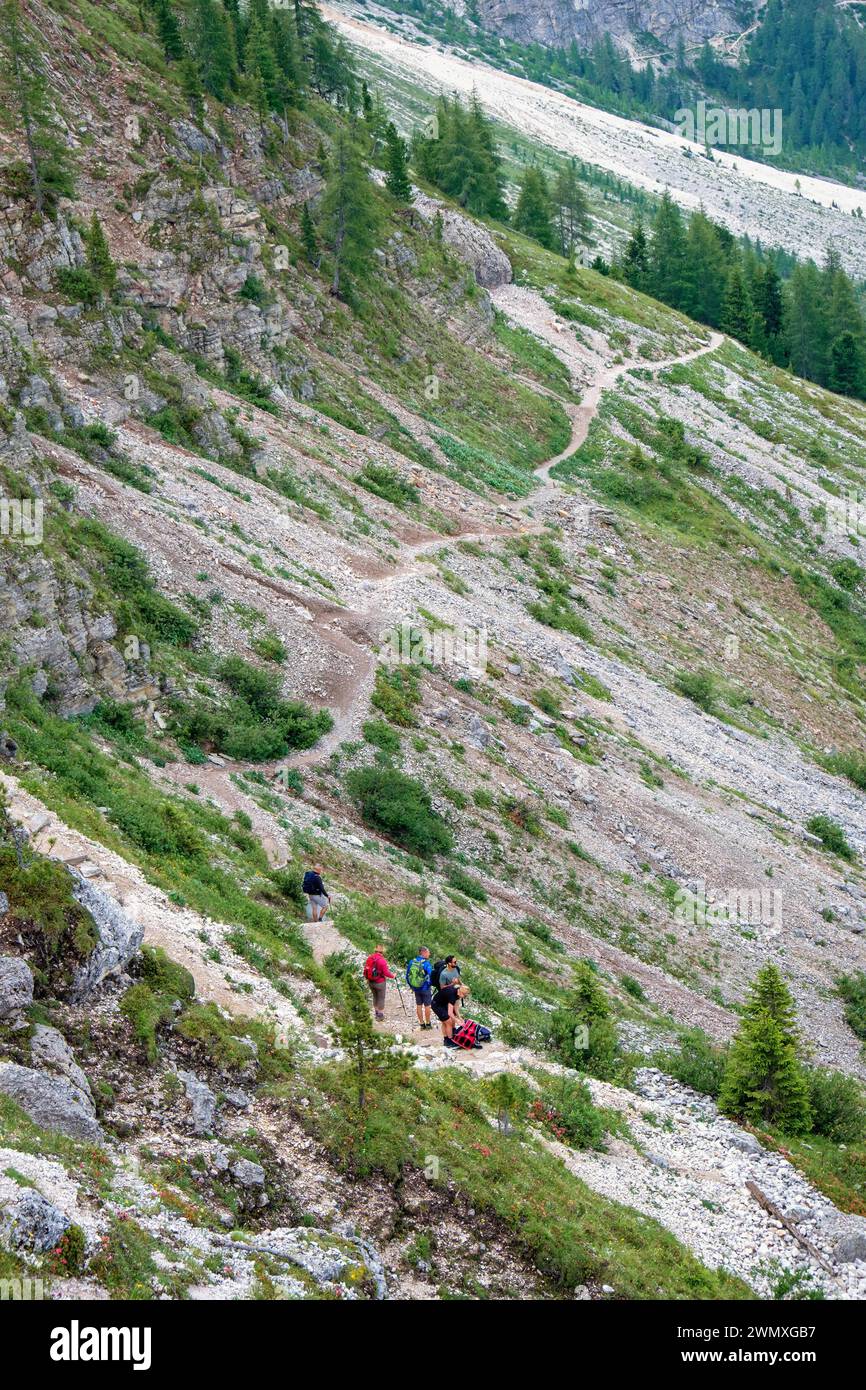 Hikers walking on a mountain path in a rocky slope in the dolomites mountains, Santa Cristina, Val Gardena, Italy Stock Photo