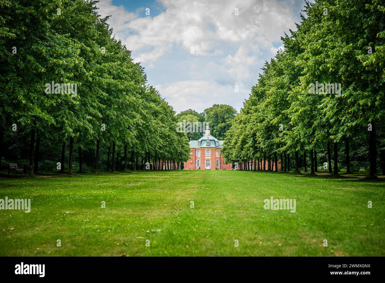 Classic red castle surrounded by green trees under a clear sky, Clemenswerth Castle, Soegel, Lower Saxony Stock Photo