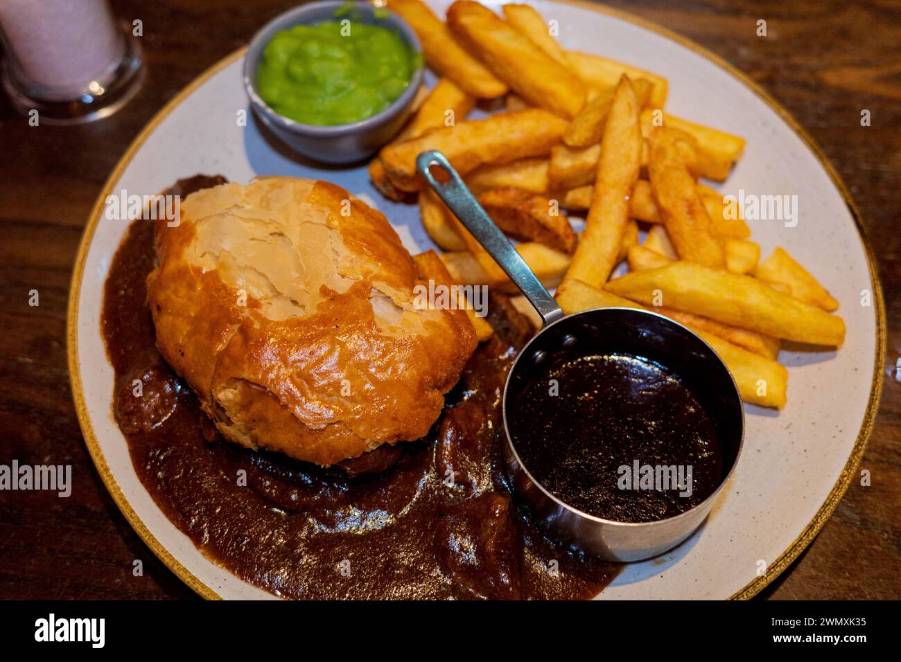 Edinburgh steak and ale pie and a pint in a Scottish pub with chips, gravy and mushy peas Stock Photo