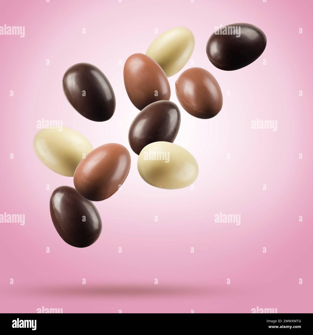 Chocolate easter eggs floating on pink background. Stock Photo