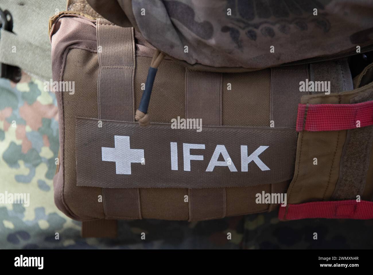 A brown military bag labelled 'IFAK' attached to a camouflage uniform, First Aid Kit, First Aid Bag, Germany Stock Photo