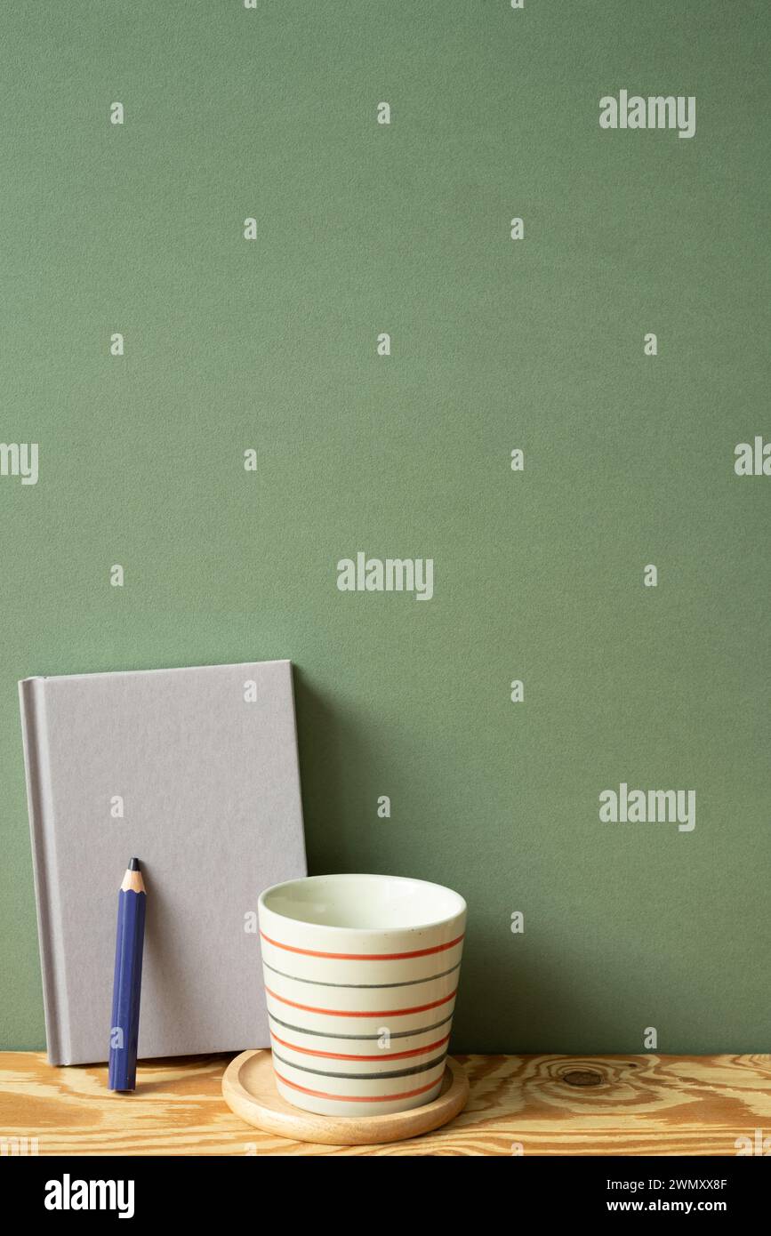 Purple diary notebook, pencil, cup on wooden desk. green wall background Stock Photo