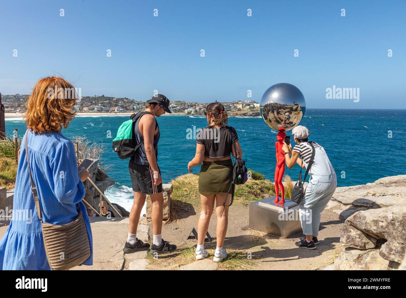 Visitors admire 'The Top of the Balance' by Chen Wenling, part of 'Sculpture by the Sea' exhibit on the coastal walk between Bondi and Tamarama beach. Stock Photo