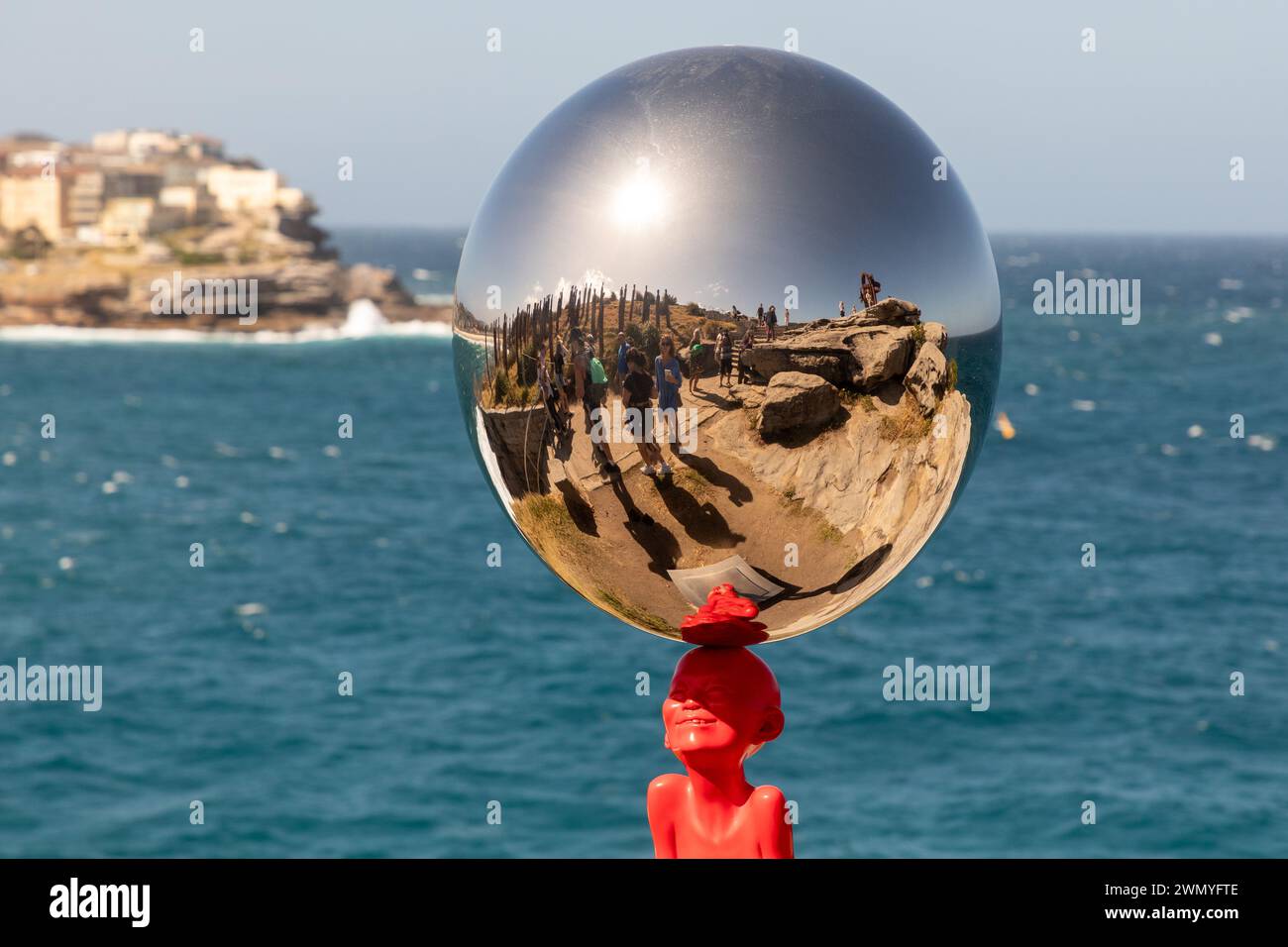 Visitors are reflected in 'The Top of the Balance' by Chen Wenling, part of the 'Sculpture by the Sea' exhibit between Bondi and Tamarama beaches. Stock Photo