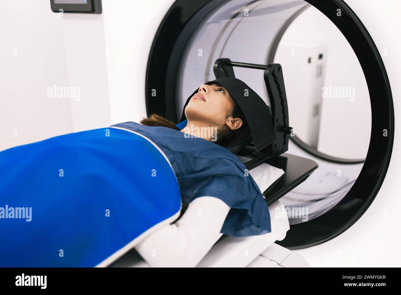 A female patient lies in a medical scanner during a magnetic resonance ...