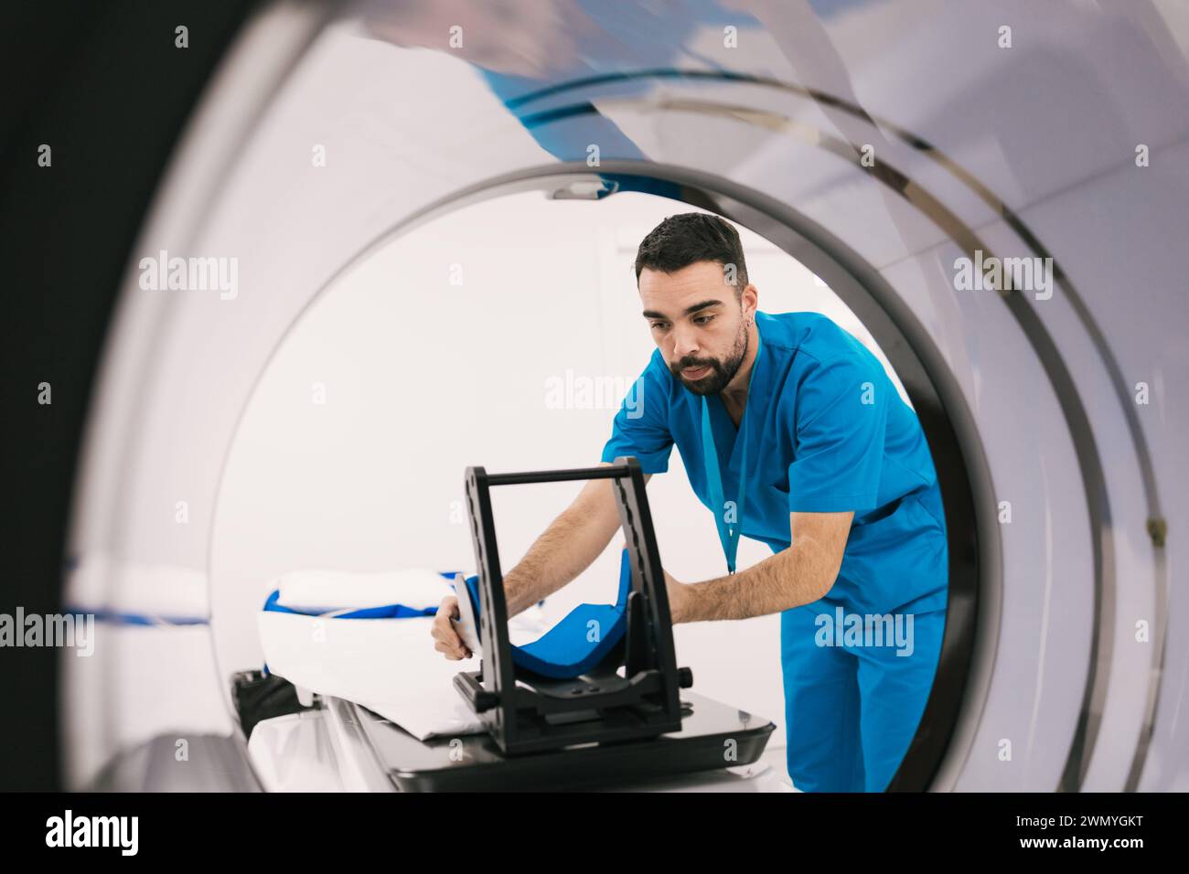 A focused medical technician is calibrating an MRI scanner in a modern