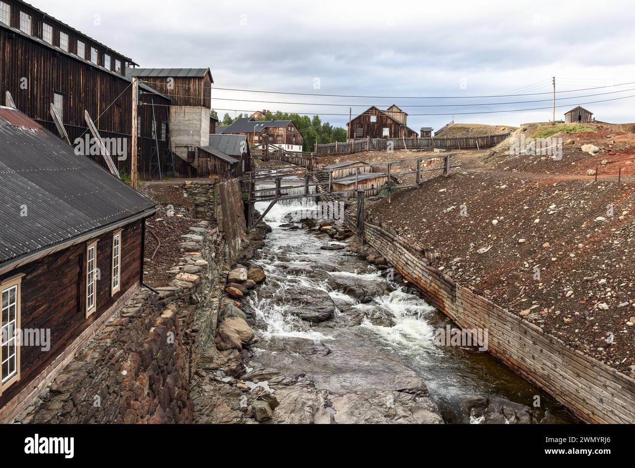Roros mining landscape, where the forceful Glomma River cuts through, framed by weathered wooden buildings and mining remnants. Norway Stock Photo