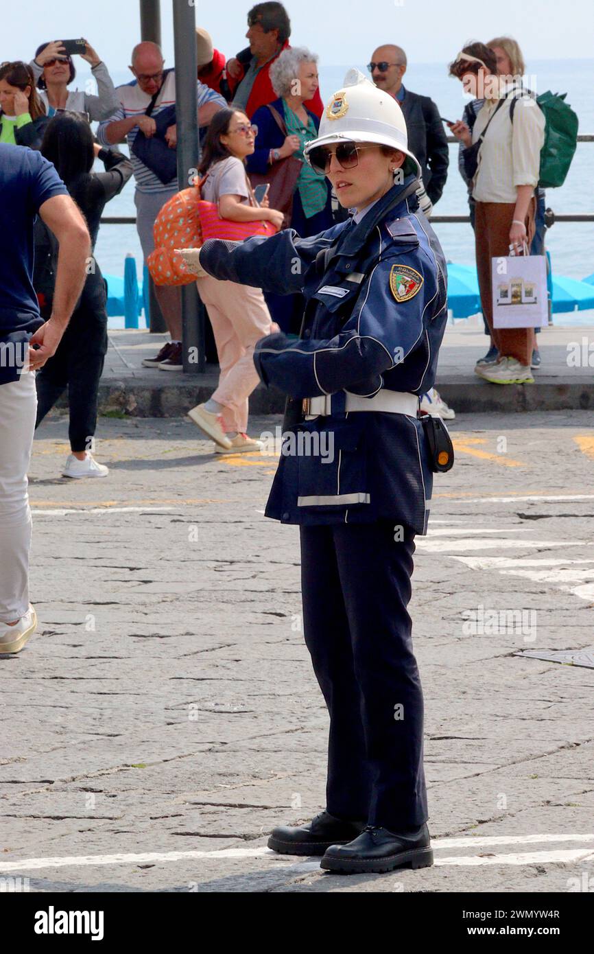 An Italian female traffic officer waves vehicles on due to parking congestion at Amalfi harbour during a busy Bank holiday. Stock Photo