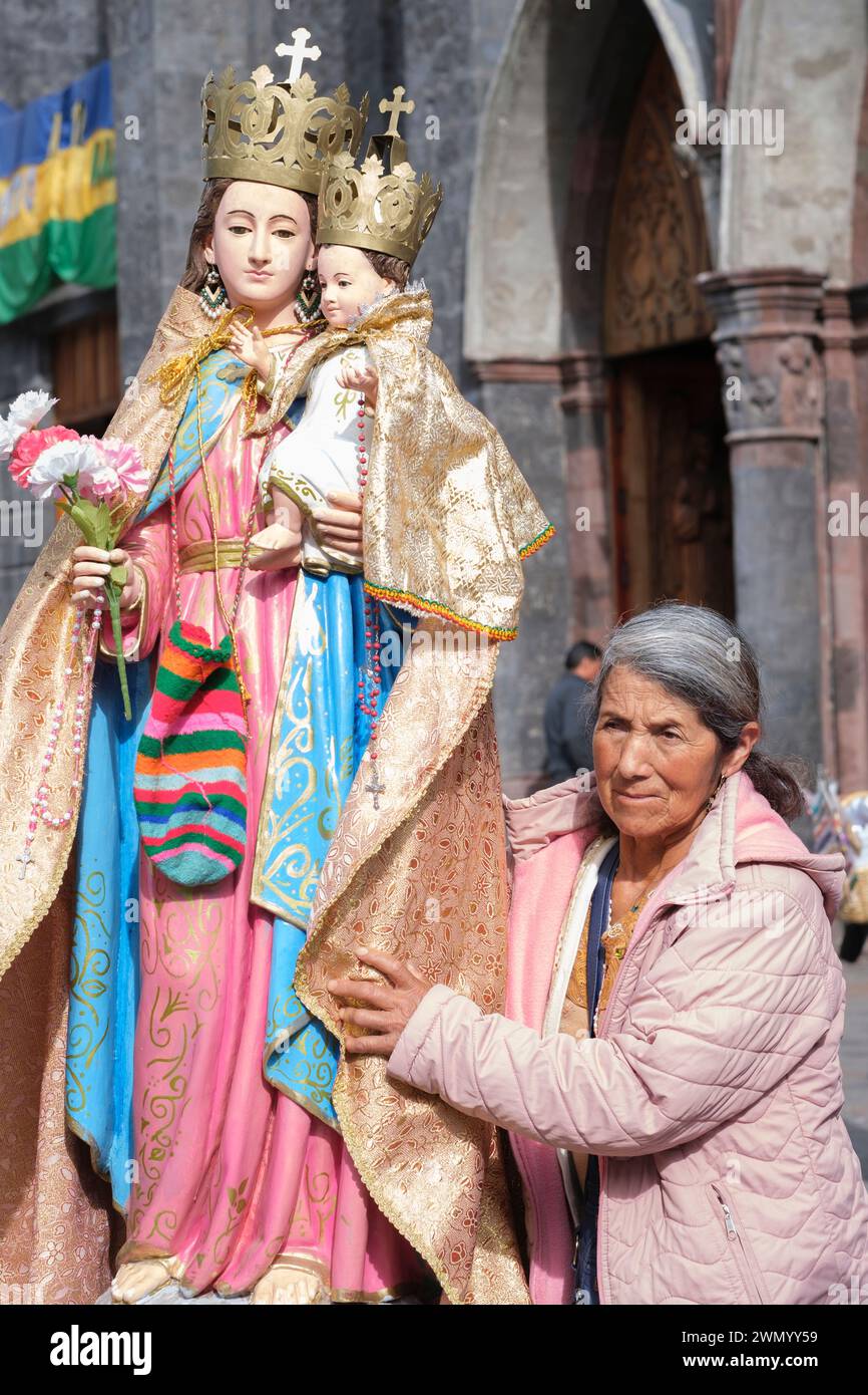 An old woman holds a statue of the Virgin Mary and the Holy Child Stock Photo