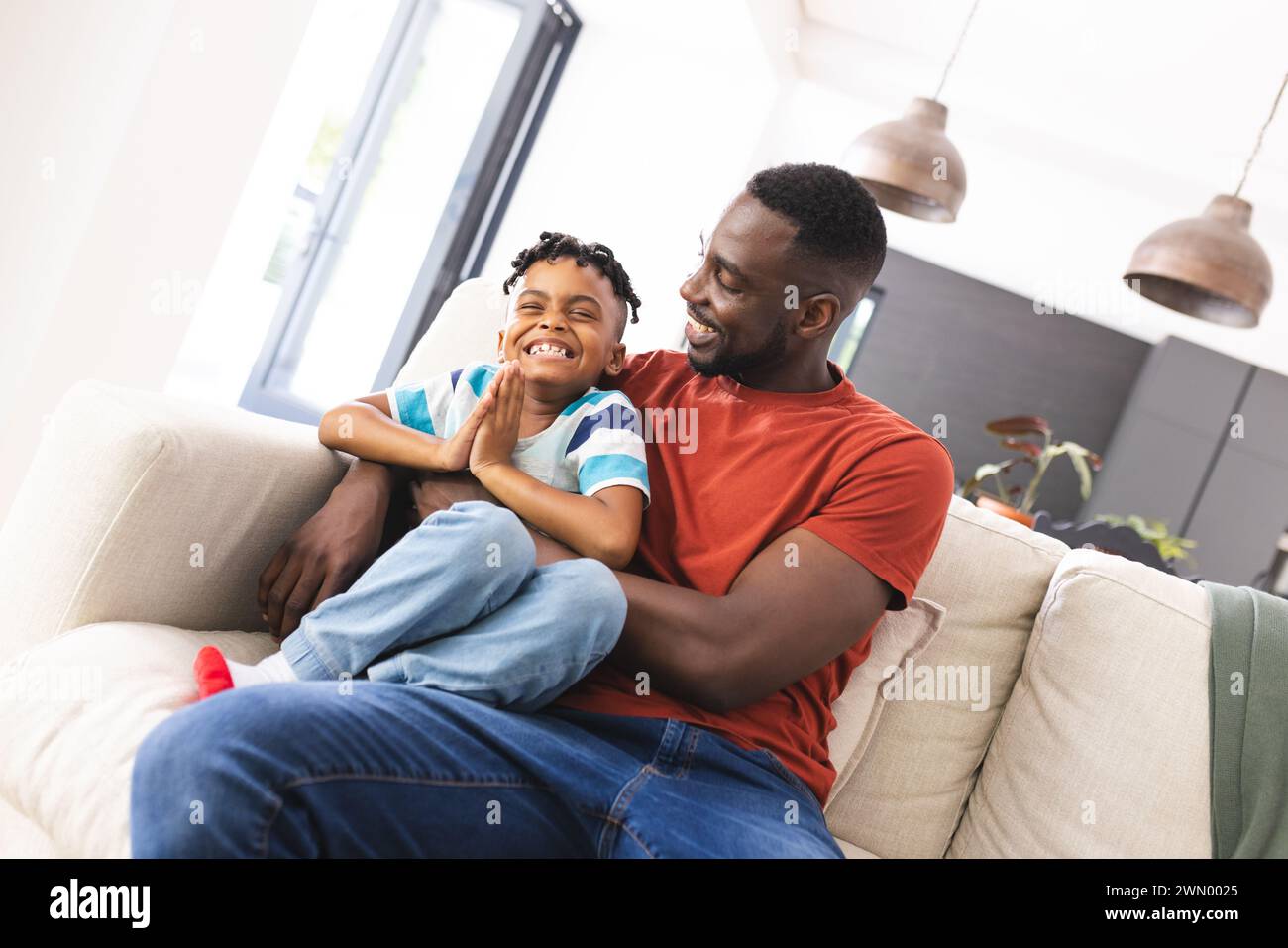 African American father and son share a joyful moment on a sofa Stock Photo