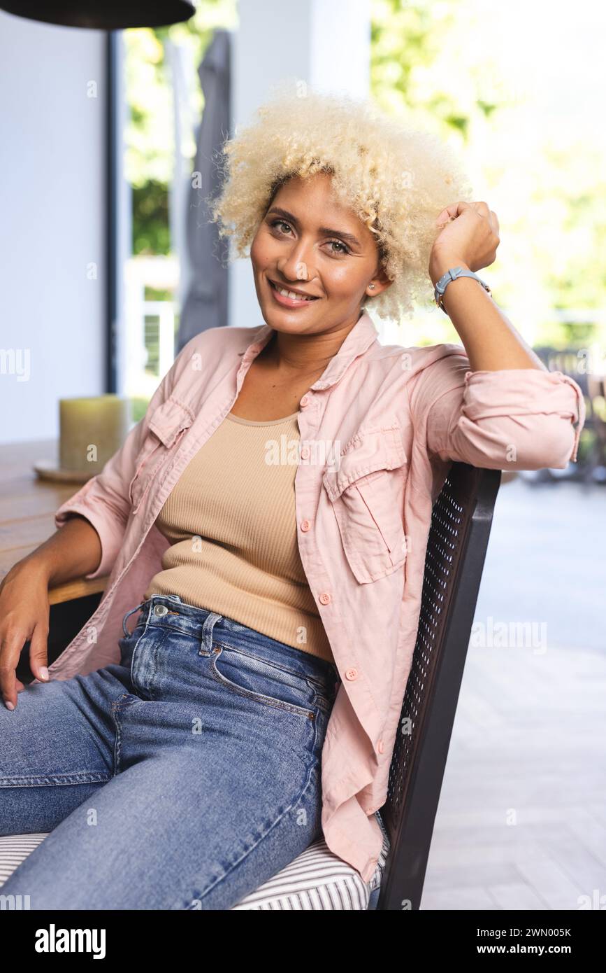 Young biracial woman with curly blonde hair smiles while seated Stock ...