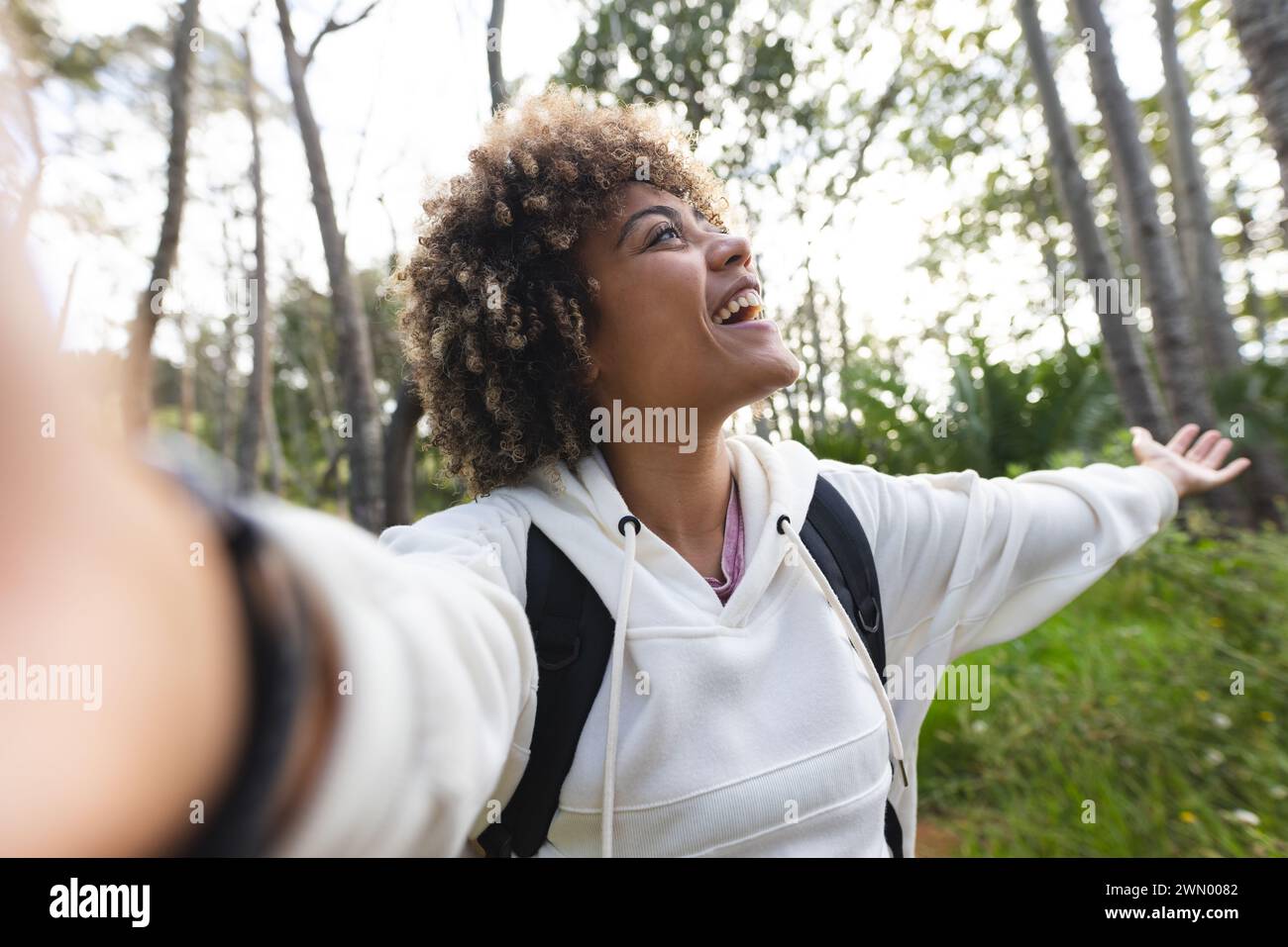 Young biracial woman with curly hair takes a selfie in the woods on a hike Stock Photo