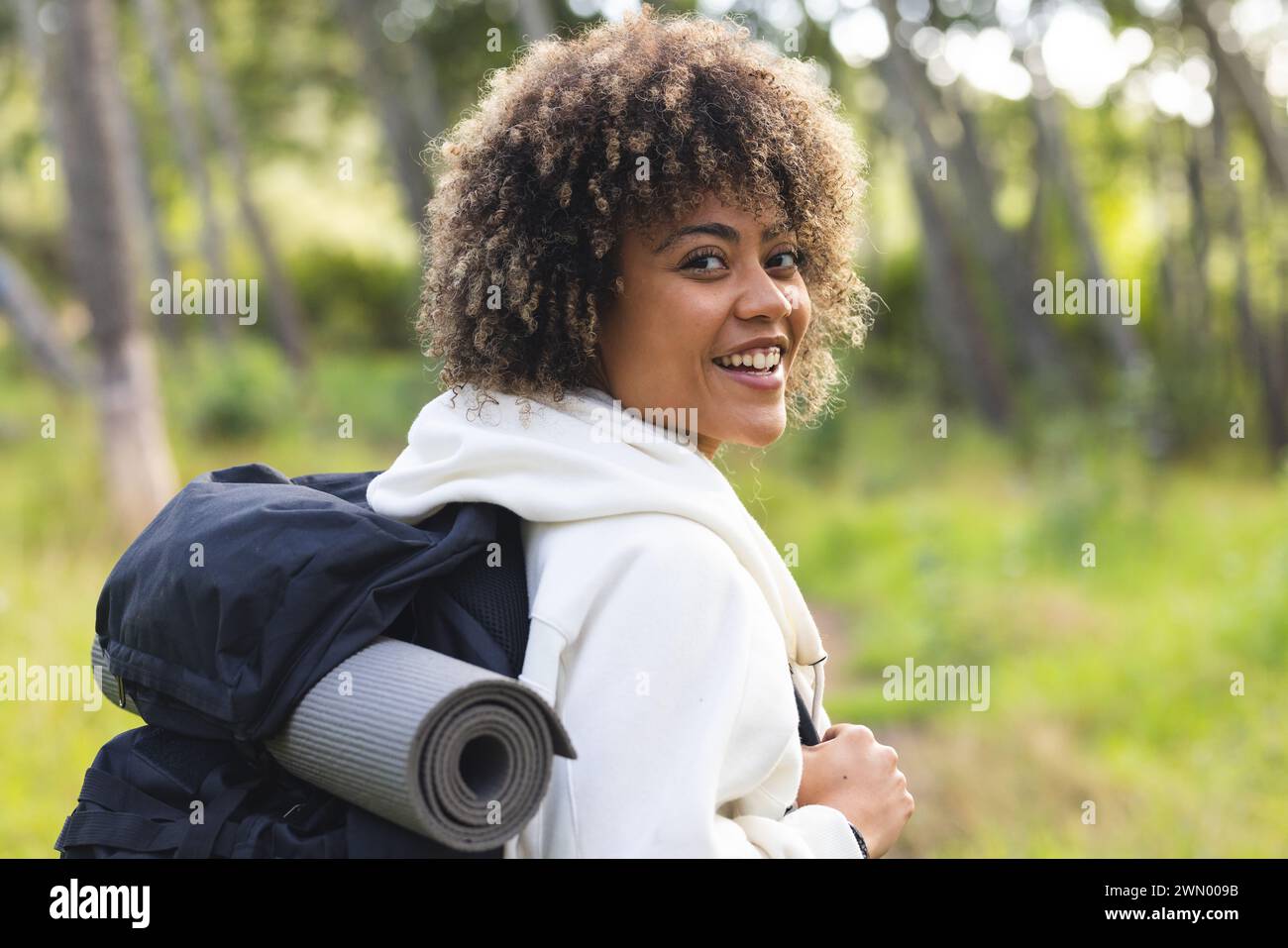 A young biracial woman with curly hair smiles while on a hike Stock ...
