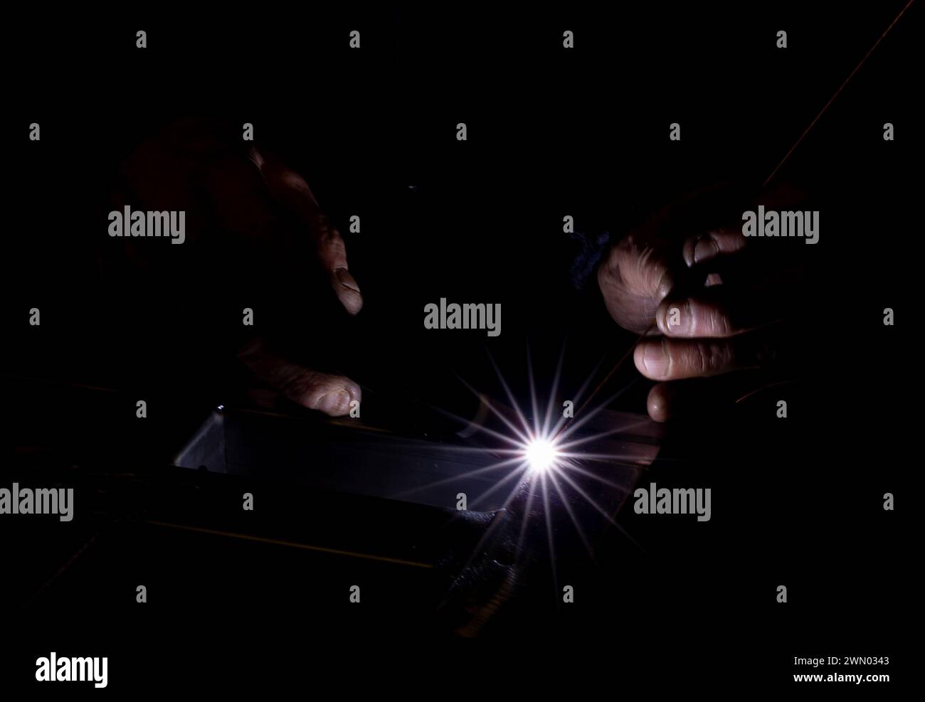 A man using a machine in his workshop in darkness Stock Photo