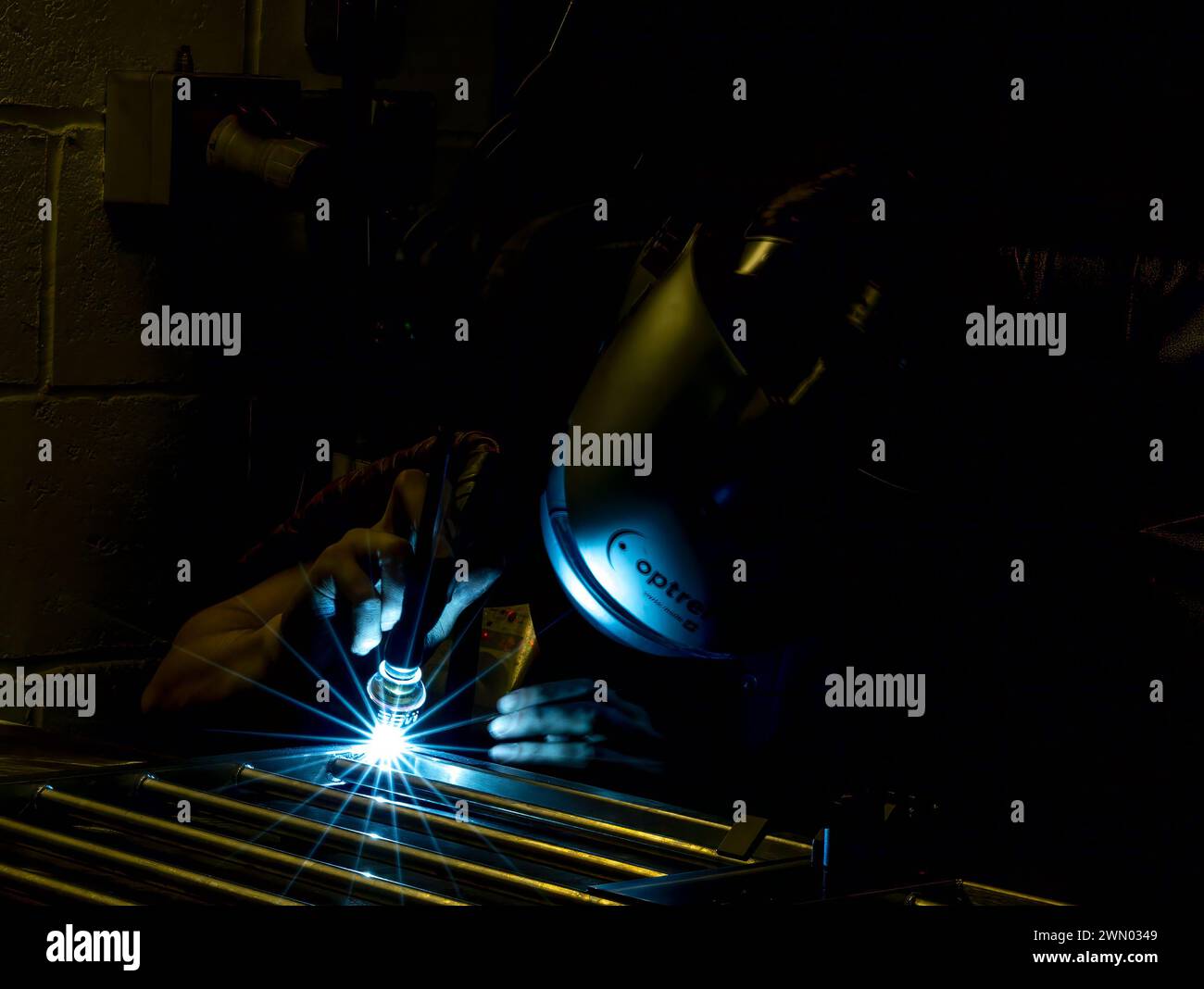 A man using a machine in his workshop in darkness Stock Photo