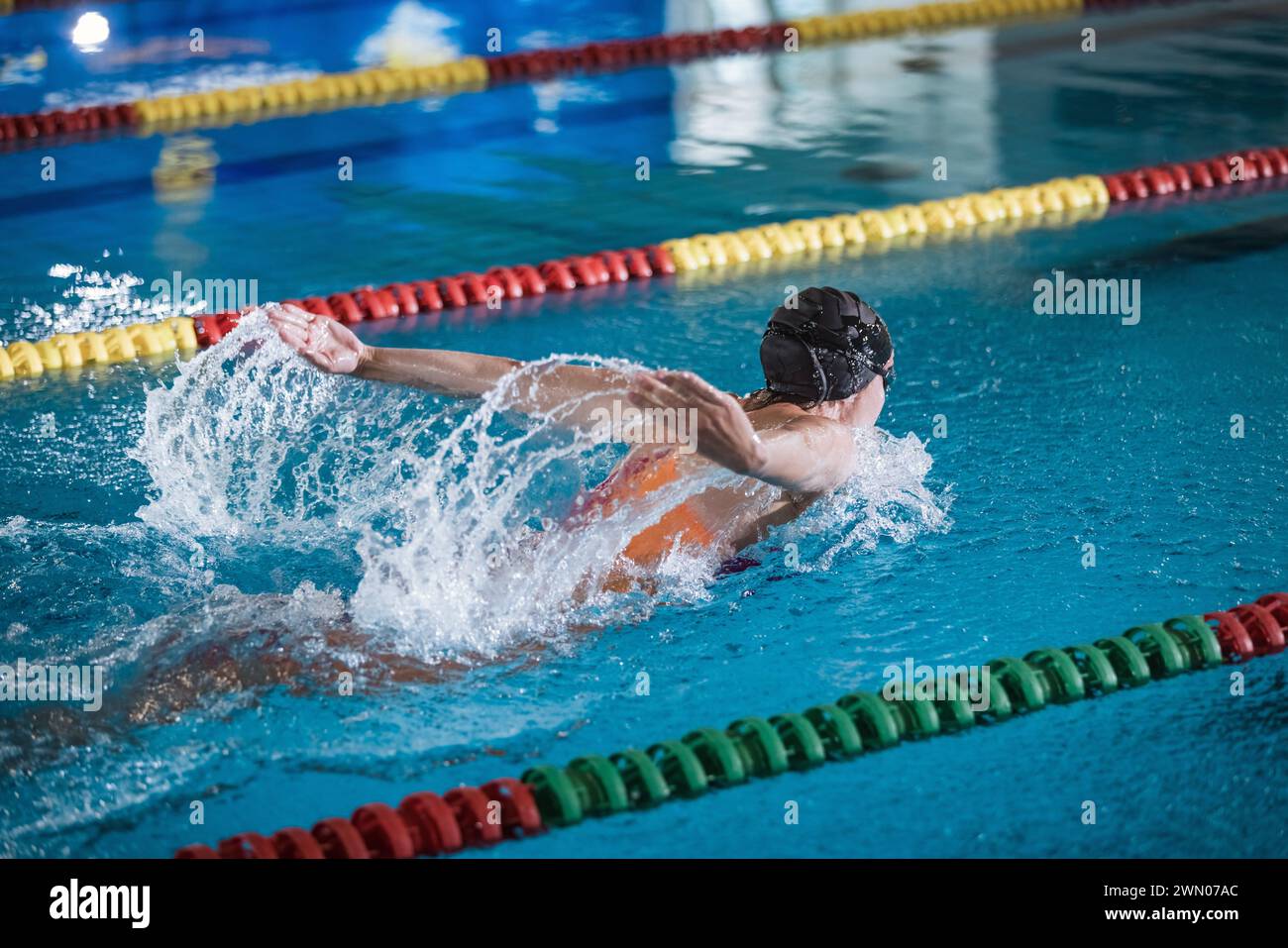 Female competitive swimmer moving through the water performing the butterfly stroke during swimming training, front view. Stock Photo