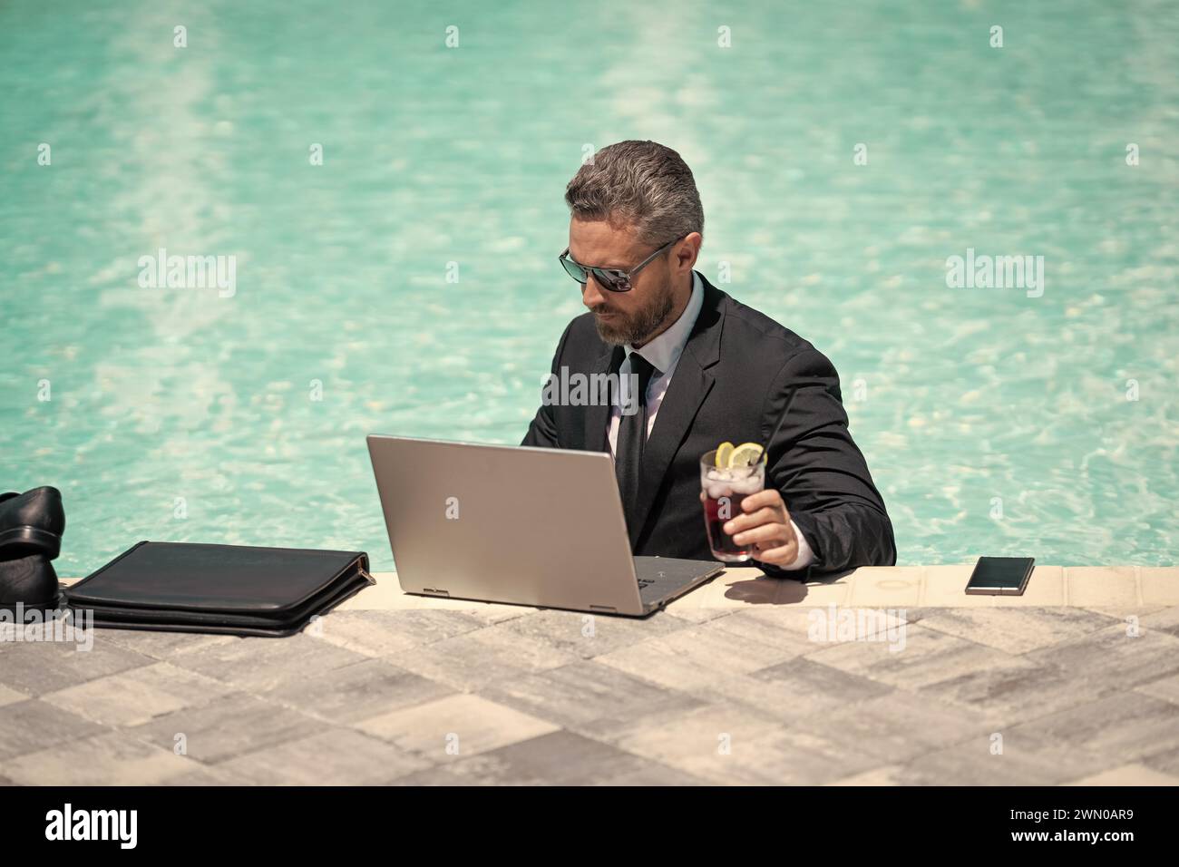 photo of busy business man working remote in summer pool. business man working remote online. business man working remote in swimming pool. business m Stock Photo