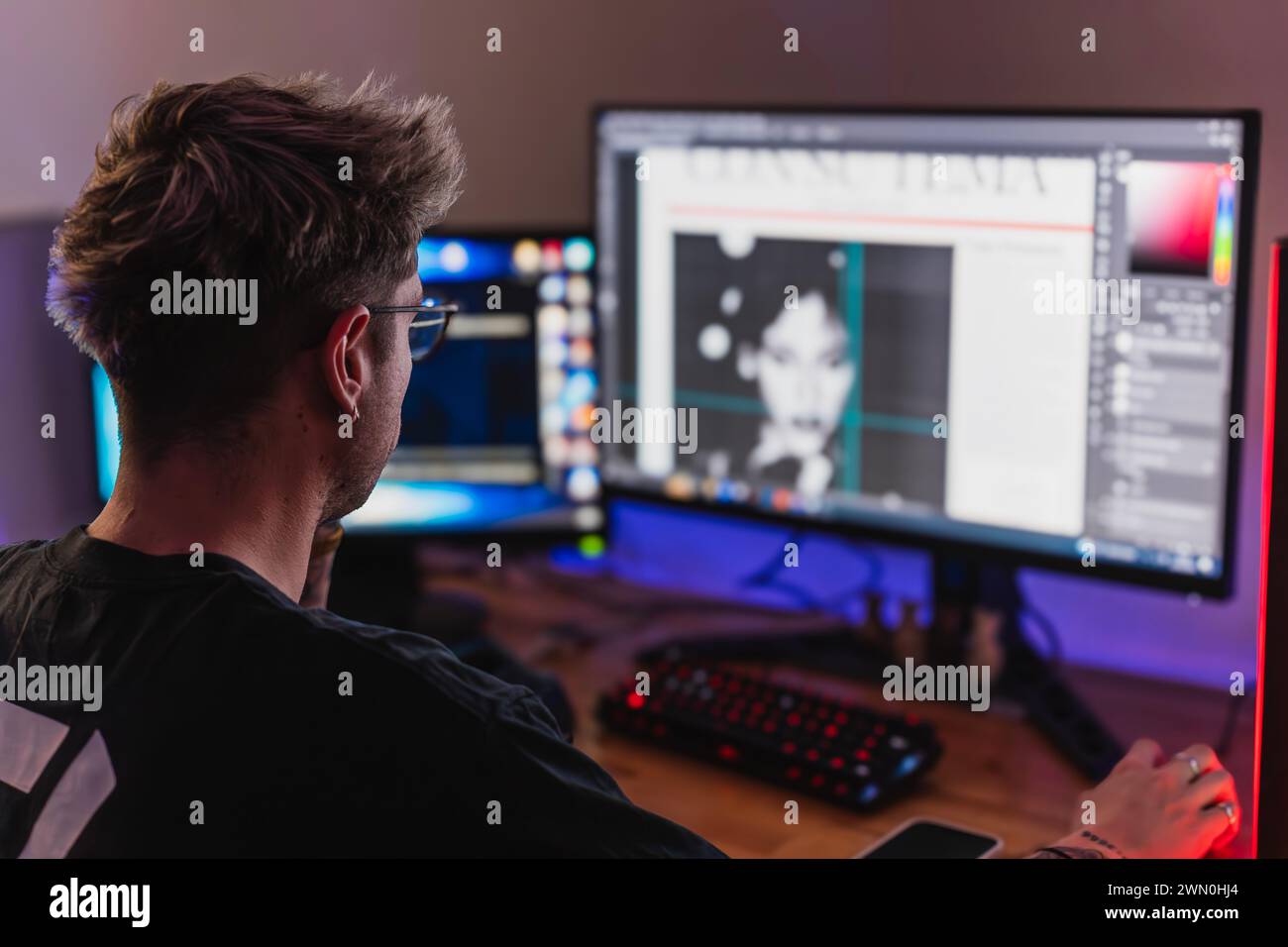 Young graphic designer working with two screens in his bedroom Stock Photo