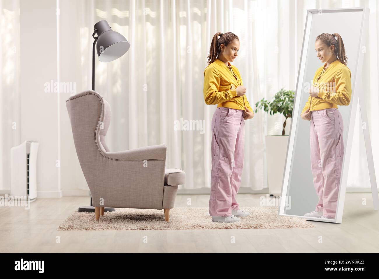 Full length shot of a teenage girl zipping her jacket in front of a mirror at home Stock Photo