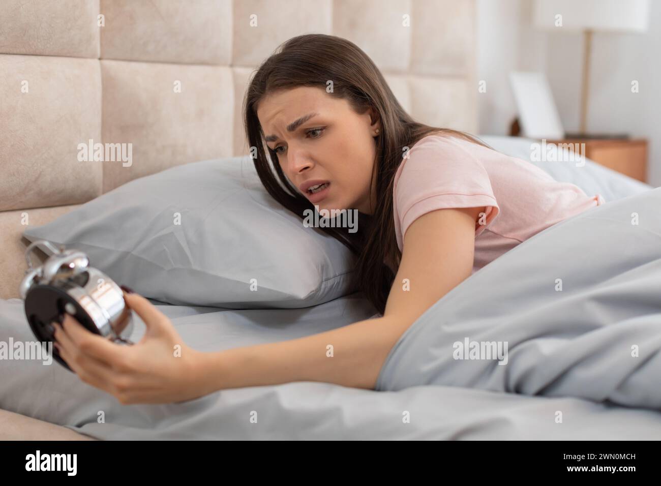 Frustrated woman waking to alarm clock noise Stock Photo